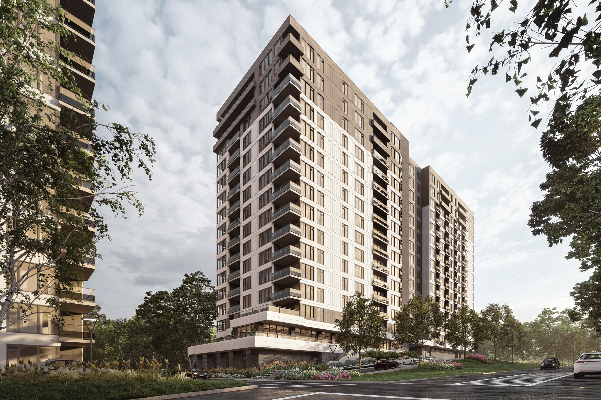 Une construction multirésidentielle contemporaine à plusieurs étages avec de nombreux balcons, se détachant sur un ciel nuageux. La structure est entourée de verdure luxuriante et de jardins paysagers, avec quelques voitures garées visibles à l'entrée. L'angle met en valeur la hauteur du bâtiment et son design moderne.