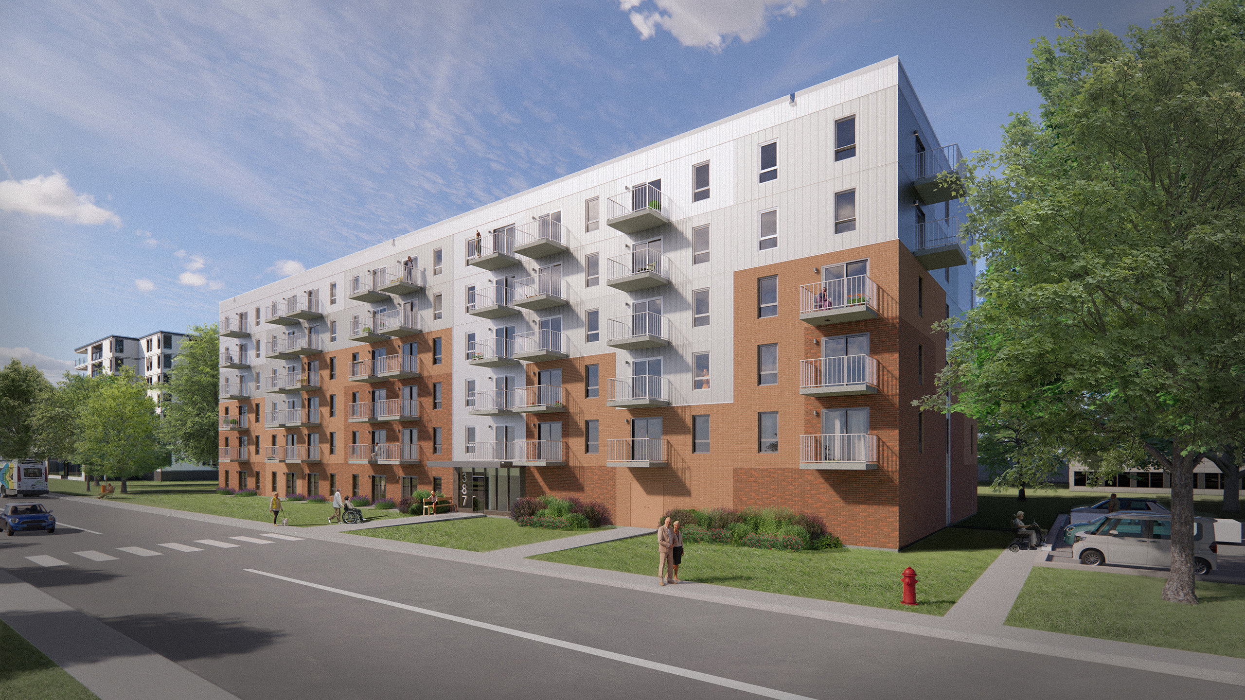 Résidence Mission Unitaînés, un immeuble de cinq étages, avec un mélange de briques et de lambris blancs, dispose de balcons à chaque niveau. Une femme marche sur un trottoir devant, et un vélo et des voitures sont garés à proximité. Des arbres et une rue avec un panneau de passage pour piétons sont visibles.