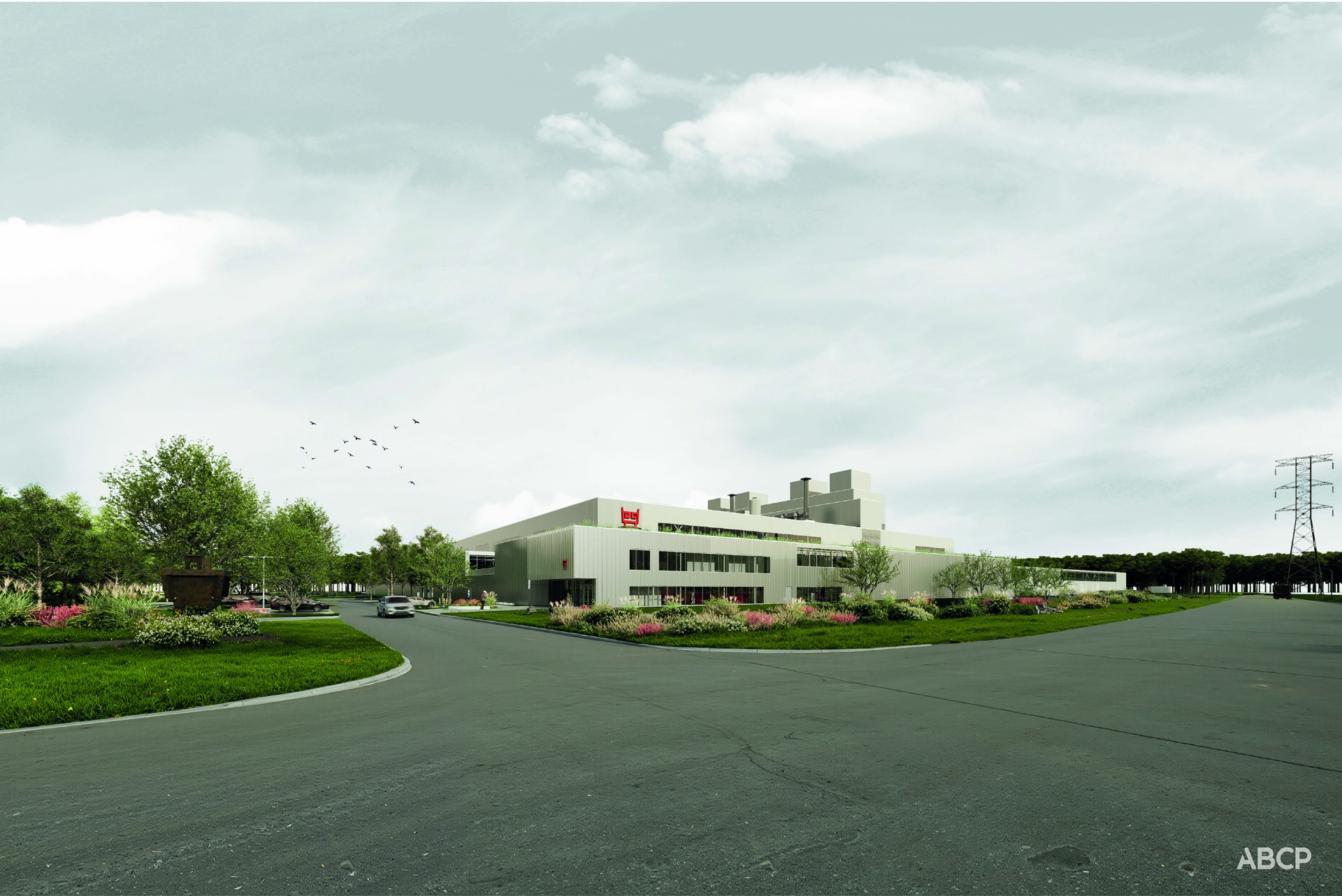 Un immeuble moderne et bas, doté de grandes fenêtres, est entouré de verdure et de jardins paysagers, près d'une large route, sous un ciel nuageux. Des oiseaux volent au-dessus du paysage et des lignes électriques sont visibles au loin.