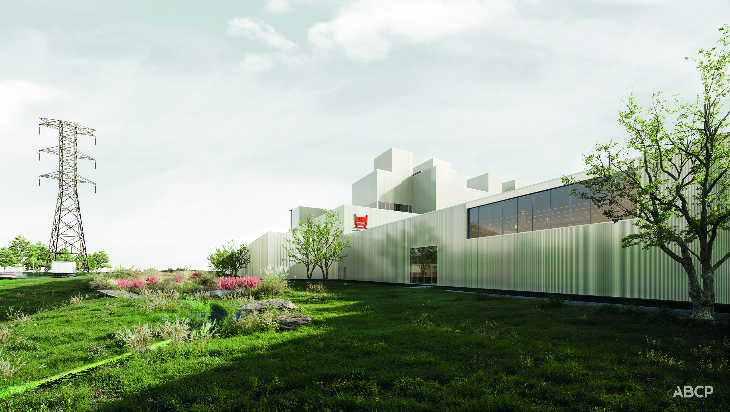Un bâtiment industriel blanc et moderne, doté de grandes fenêtres, se dresse dans un paysage verdoyant agrémenté d'arbres et d'arbustes. Un haut pylône électrique se dresse à gauche, sous un ciel nuageux. Crédit photo : ABCP.