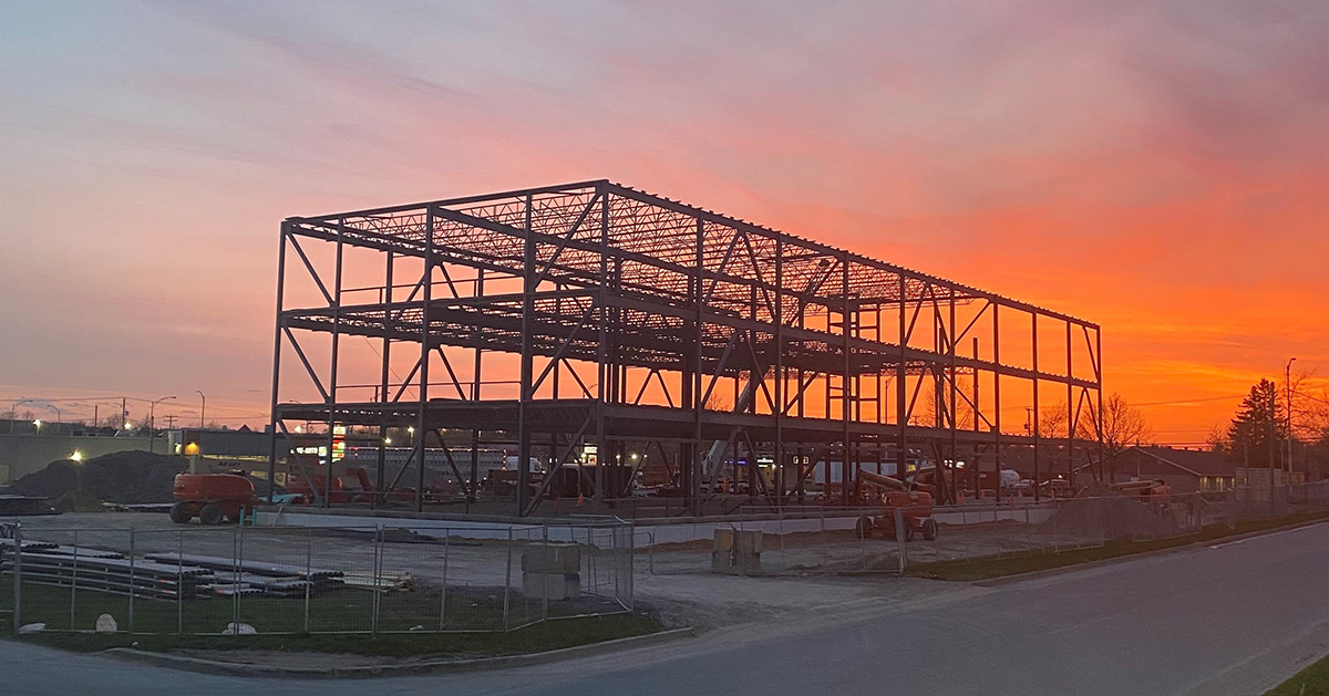 A building under construction with a sunset in the background.