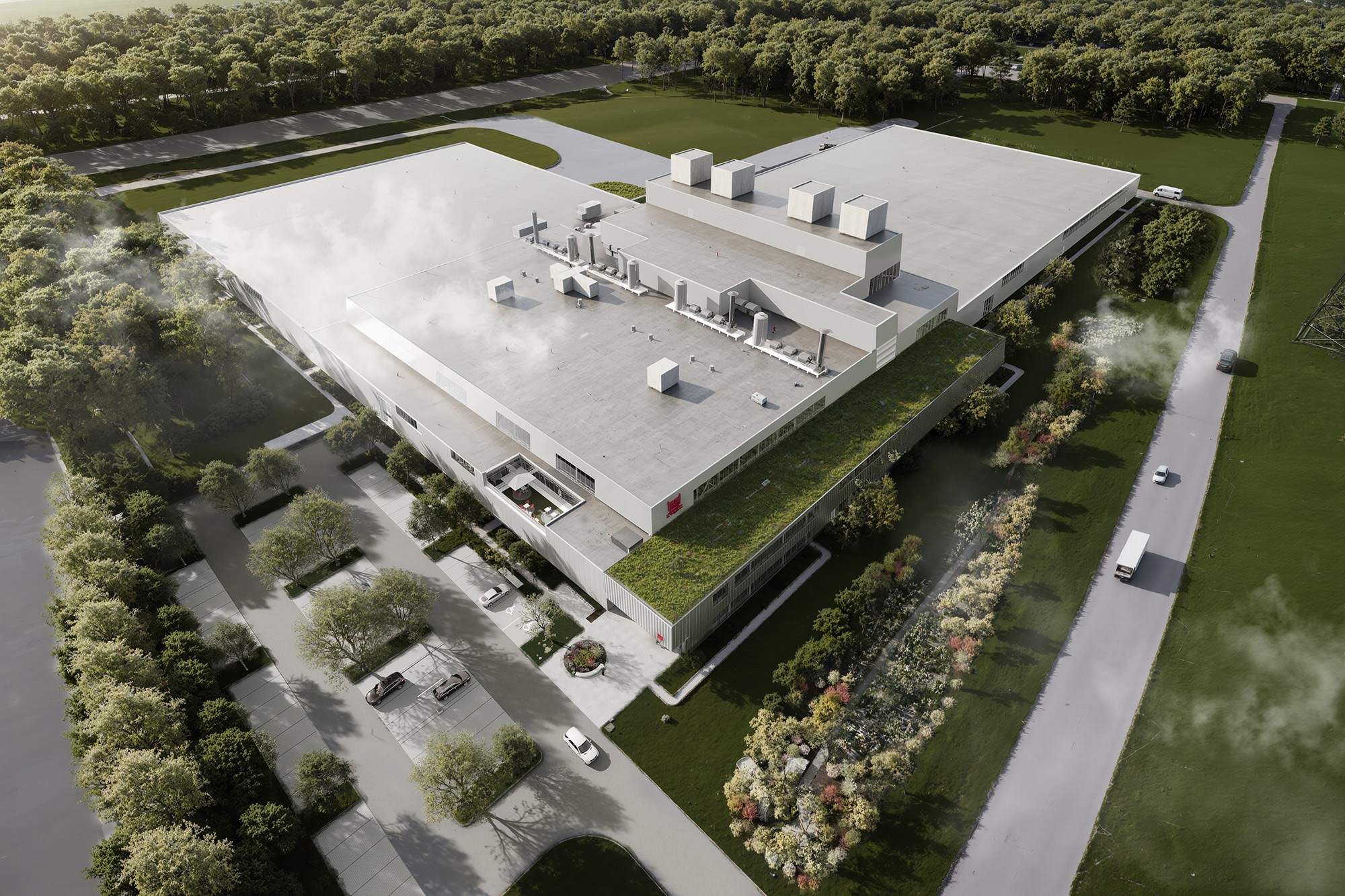 Aerial view of a large, modern industrial building surrounded by greenery, featuring a white roof, green rooftop garden, and smokestacks. Trucks are parked near the entrance—an ideal site for l’optimisation du contenu pour le référencement.